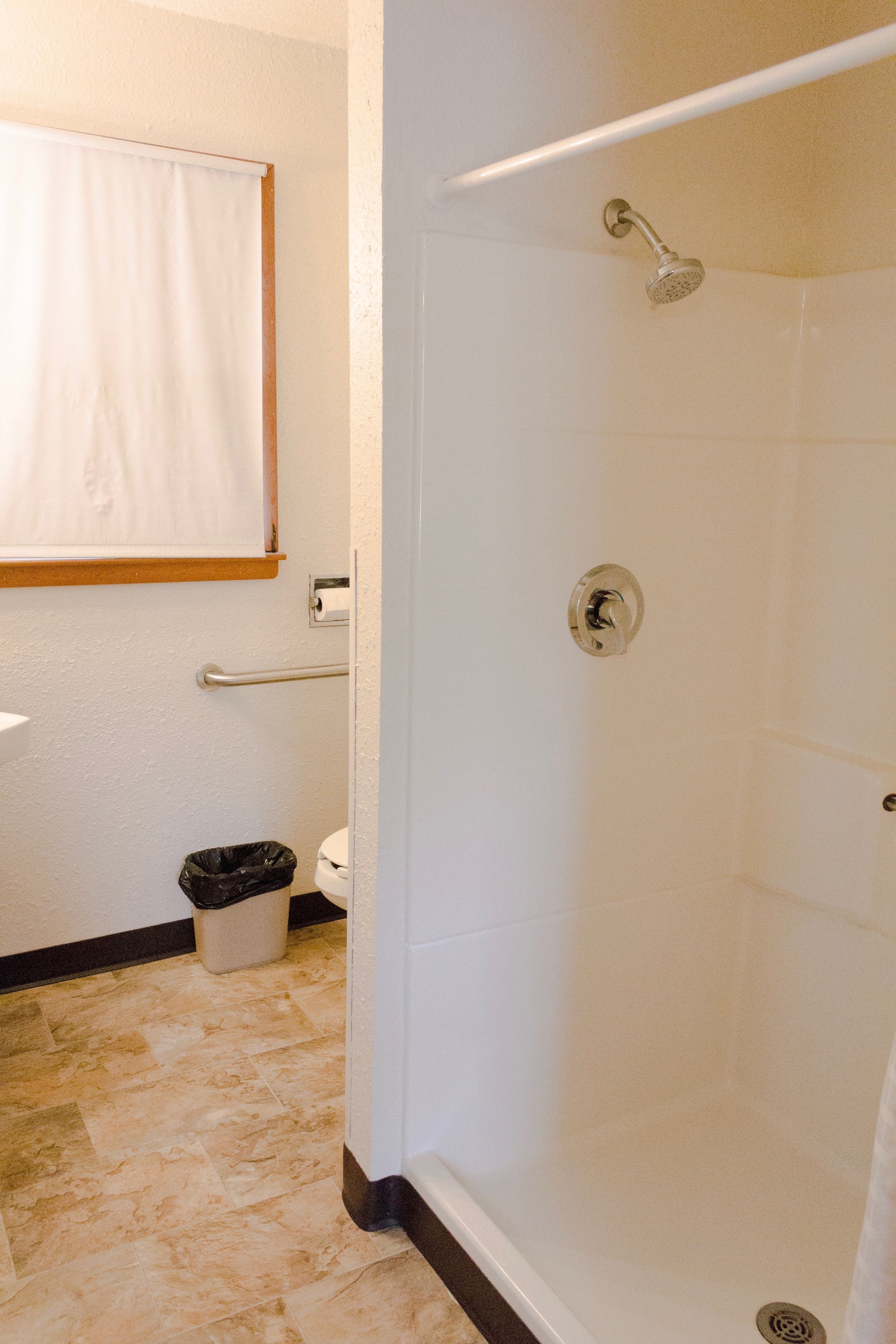 Un bagno con doccia, WC e cestino.