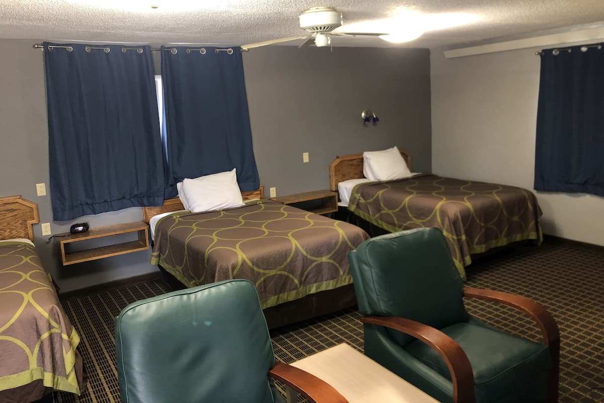 Une chambre d’hôtel avec deux lits, un ventilateur de plafond et une petite table avec une chaise.