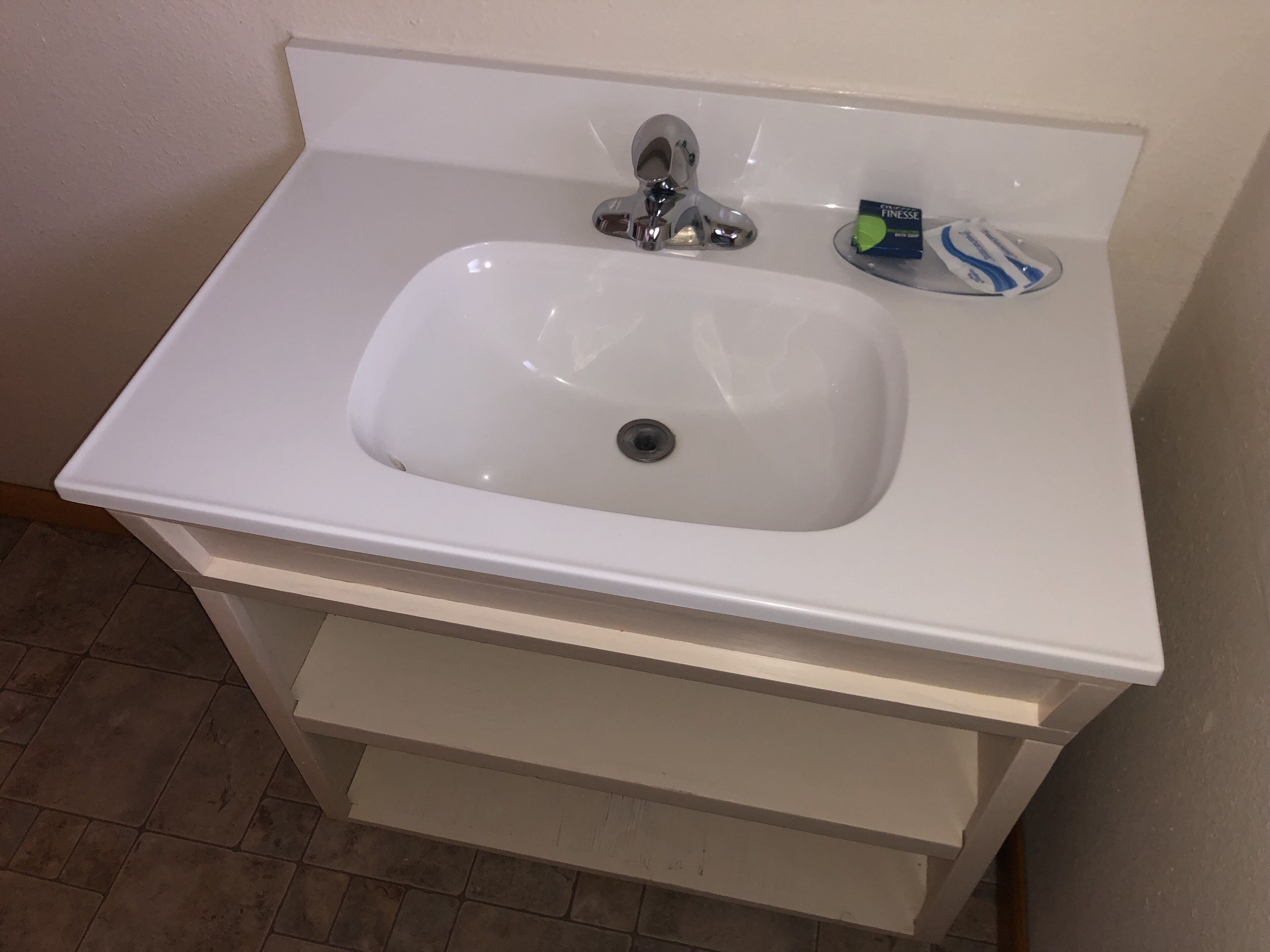 A white bathroom sink with a chrome faucet, a soap dish, and a toothbrush holder.