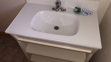 A white bathroom sink with a chrome faucet, a soap dish, and a toothbrush holder.