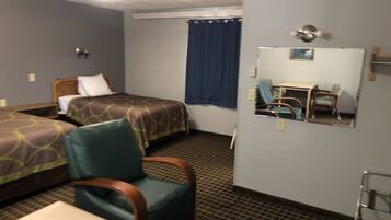 A hotel room with two beds, a chair, a desk, a mirror, and a window with a curtain.