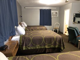 Habitación de hotel con dos camas, una silla, un escritorio y una ventana con cortinas.