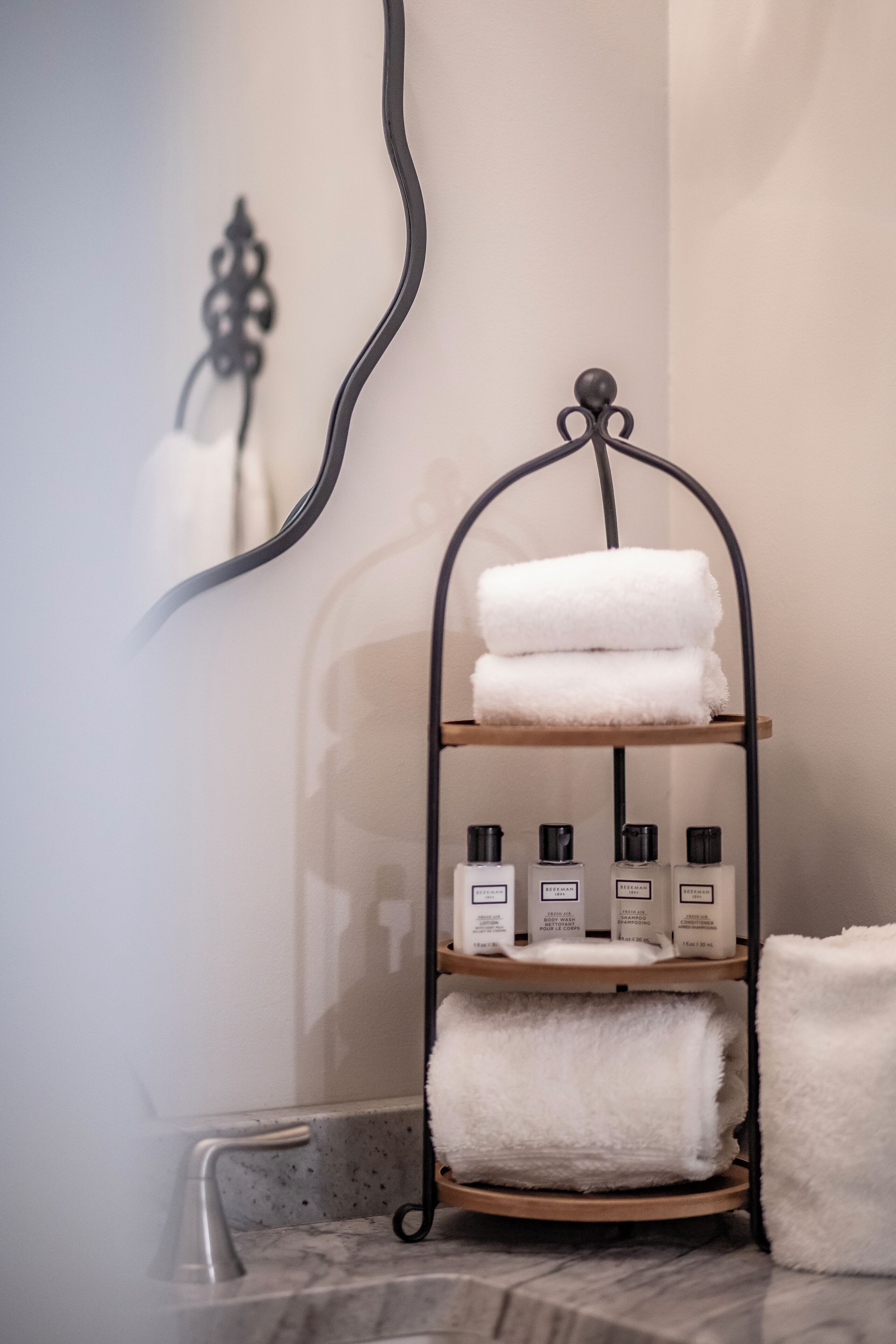 Une salle de bain avec un porte-serviettes où sont rangées des serviettes pliées et des articles de toilette.