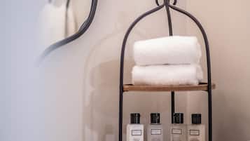 Une salle de bain avec un porte-serviettes où sont rangées des serviettes pliées et des articles de toilette.