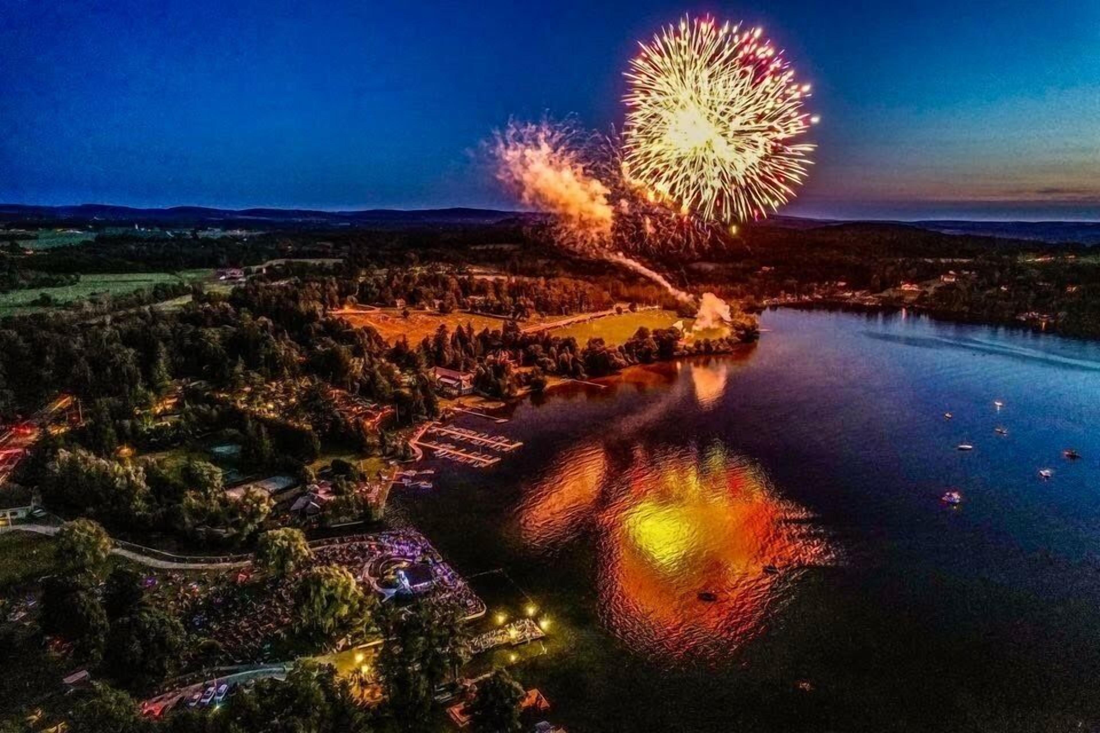 Vista aerea di una zona sul lago con fuochi d'artificio, un molo e un parco con vialetti.