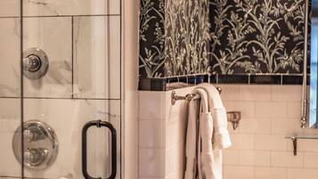 A bathroom with a glass-enclosed shower, a white sink, and a decorative wall with floral patterns.
