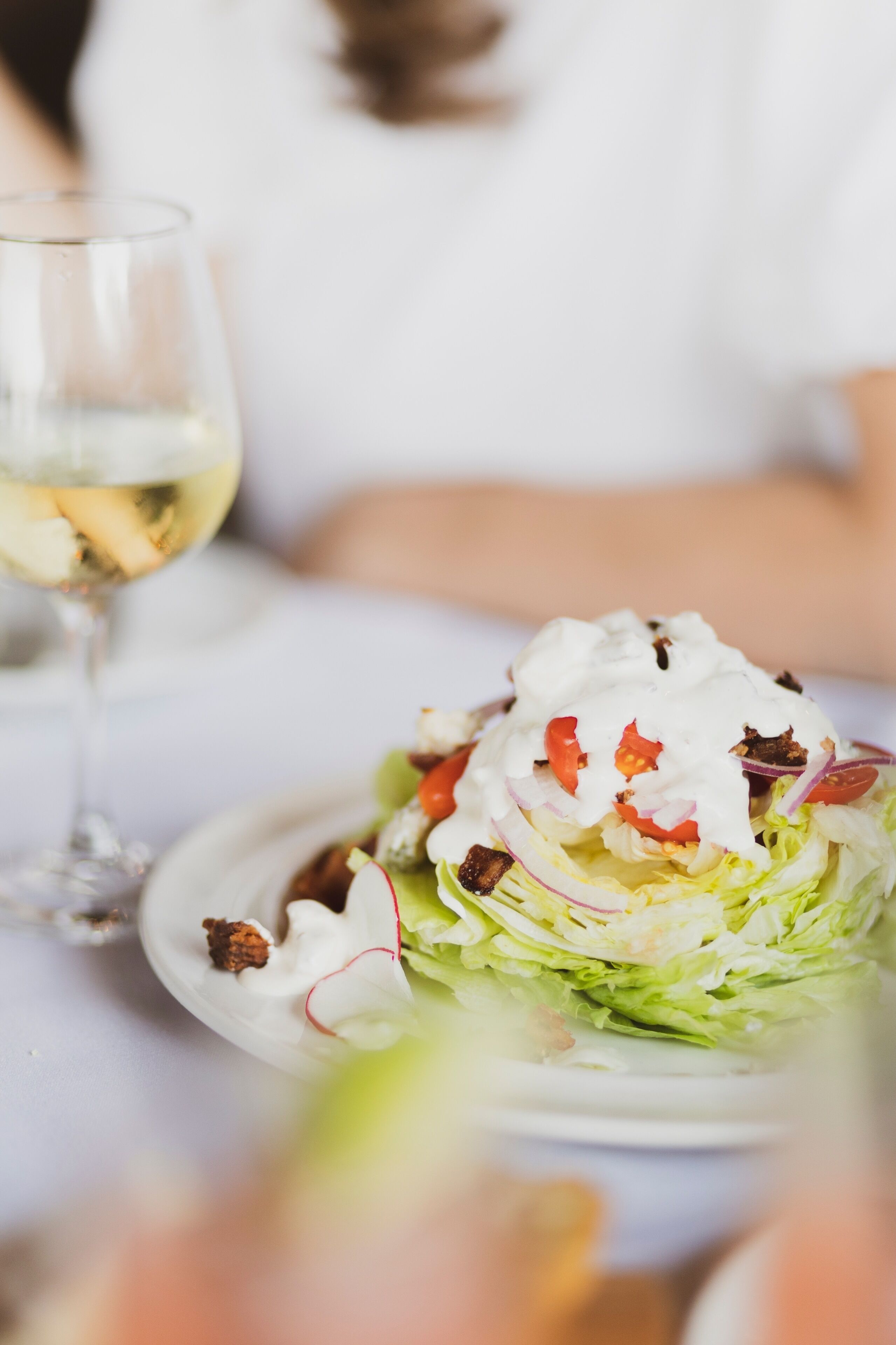 A salad with a creamy topping on a white plate.