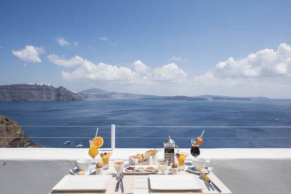 A table set for breakfast with a view of the sea and cliffs.