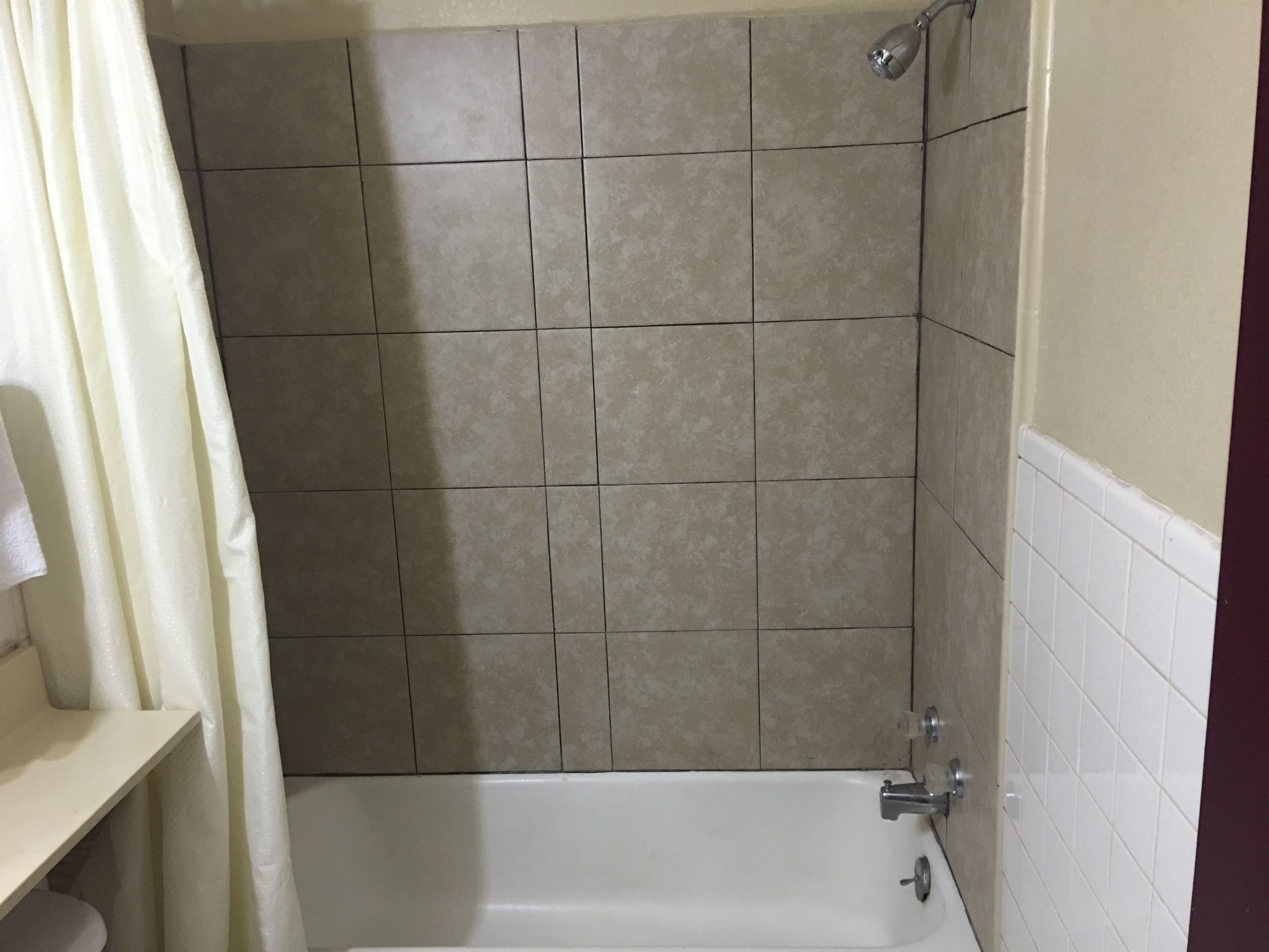 A bathroom with a bathtub, tiled walls, and a showerhead.