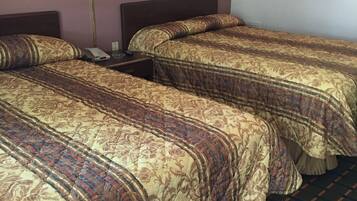 Una habitación de hotel con dos camas, una mesita de noche, una lámpara y un cuadro en la pared.
