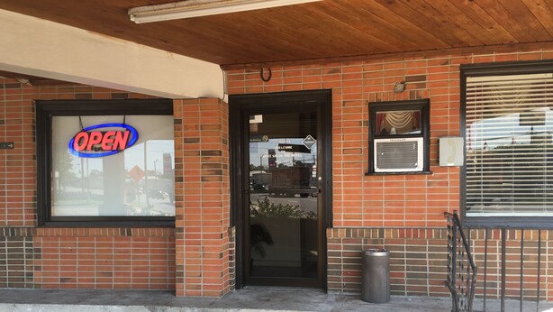 A brick building with a large 'OPEN' sign, a black door, and a small trash can outside. - Best Value Inn Motel Sandusky (Marianna)