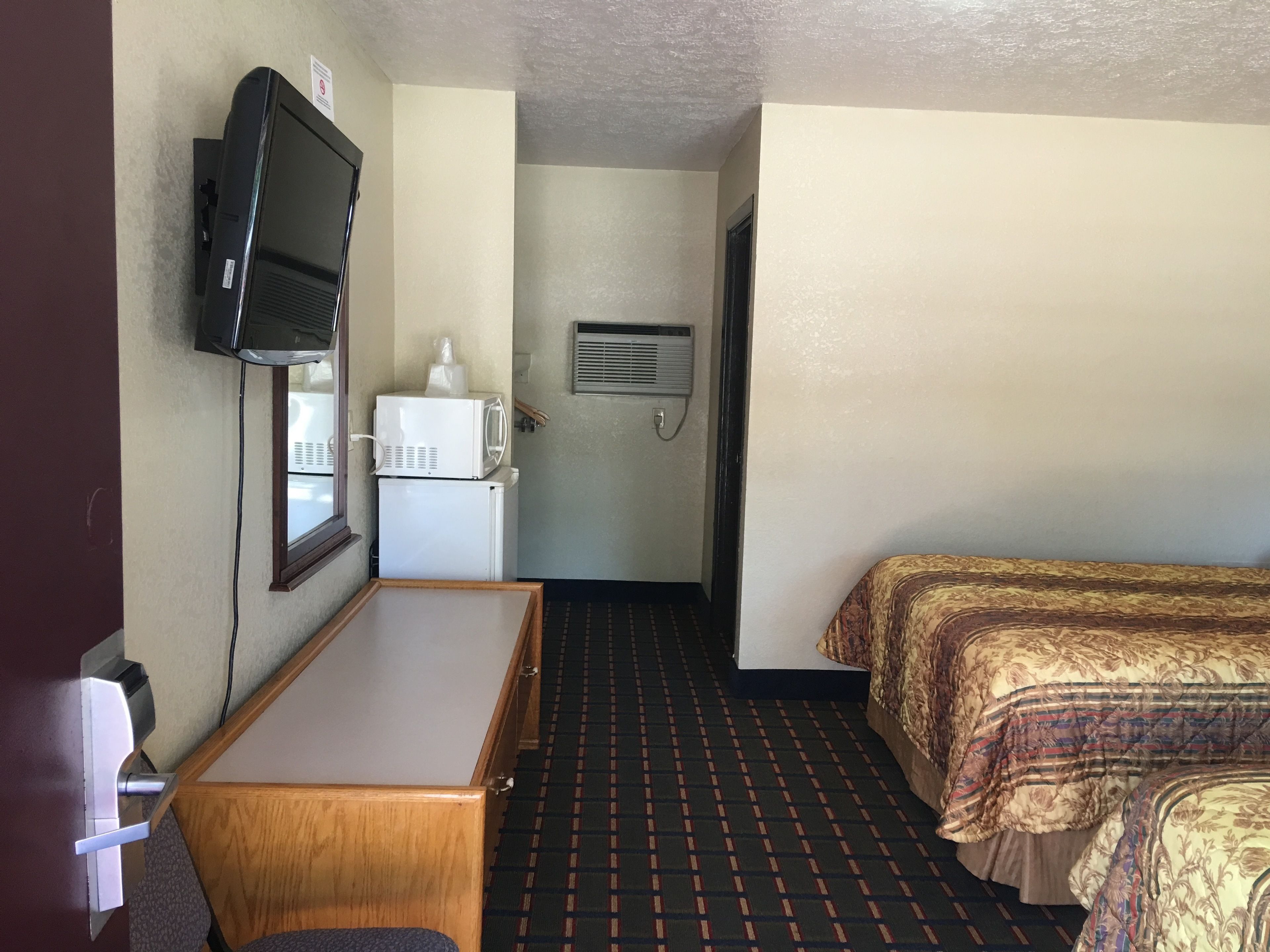 Une chambre d’hôtel équipée d’un lit, d’un bureau, d’une télévision, d’un four à micro-ondes et d’un réfrigérateur.