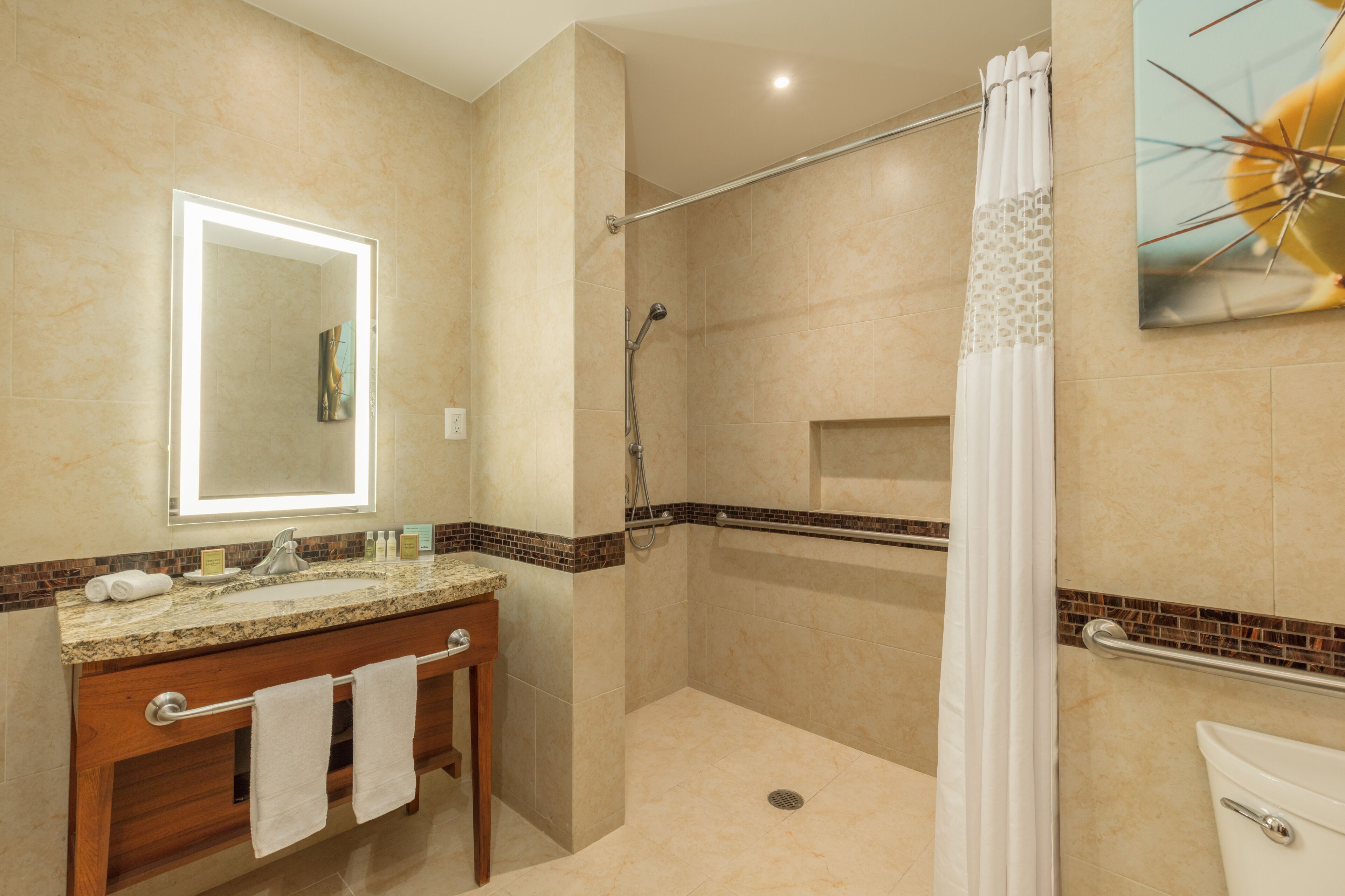 Un baño moderno con encimera de granito, tocador de madera, espejo grande, ducha con puerta de cristal y un inodoro.