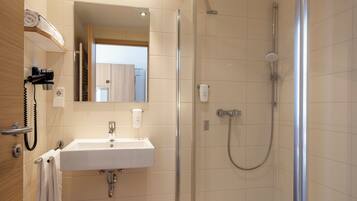A modern bathroom with a glass-enclosed shower, a white sink, and a mirror above it.