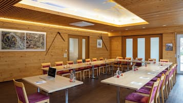 Un salón de conferencias con largas mesas, sillas y techo de madera.