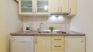 Una cocina compacta equipada con lavavajillas, cafetera, pileta y refrigerador.