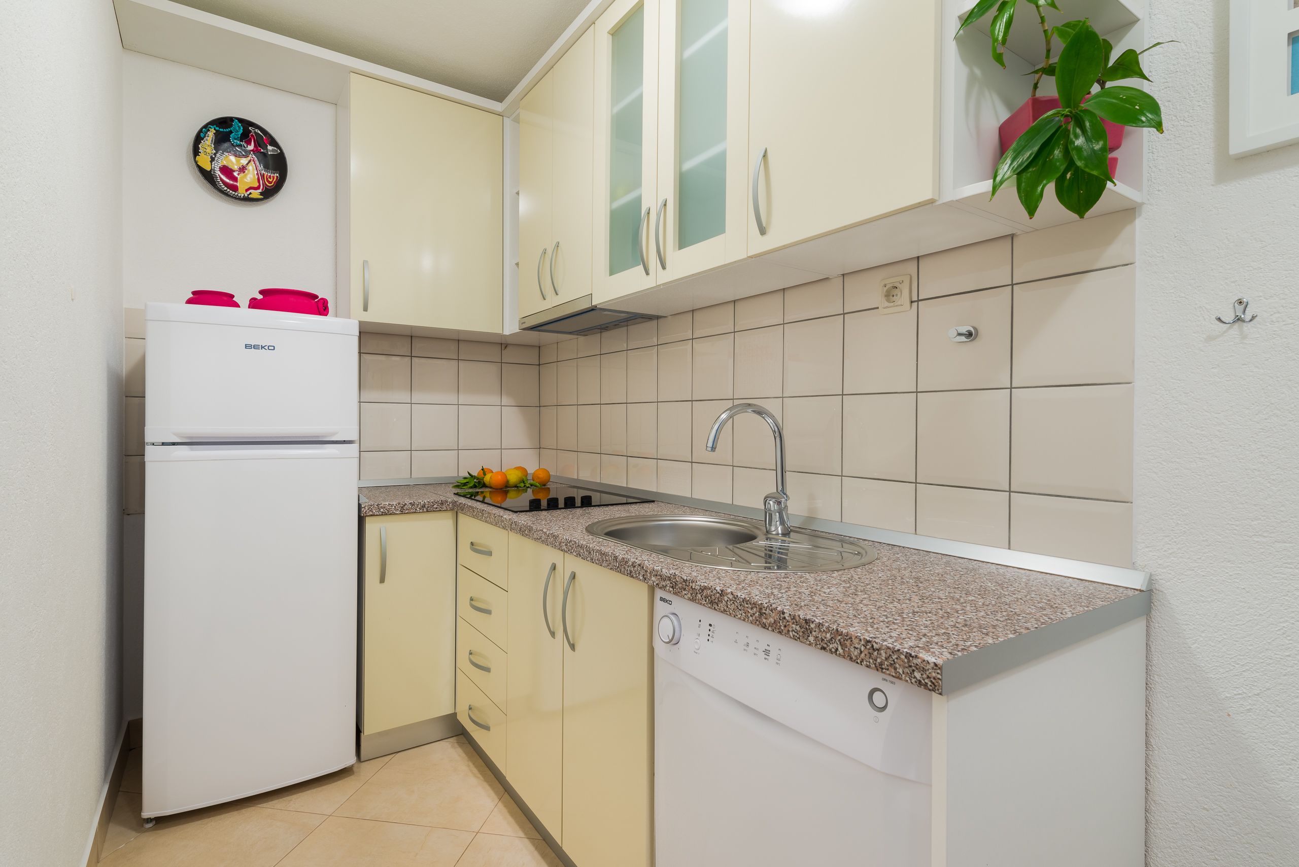A compact kitchen with a refrigerator, sink, and countertop.