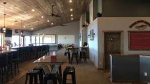 A spacious restaurant with wooden ceiling beams, multiple tables and chairs, and a bar area. - River Bend's Resort (Baudette)
