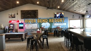 A bar area with a wooden ceiling, a large mural advertising River Bend Resort, and a television mounted on the wall. - River Bend's Resort (Baudette)