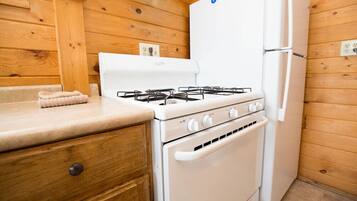 Una cocina compacta con estufa a gas, horno y refrigerador blanco.