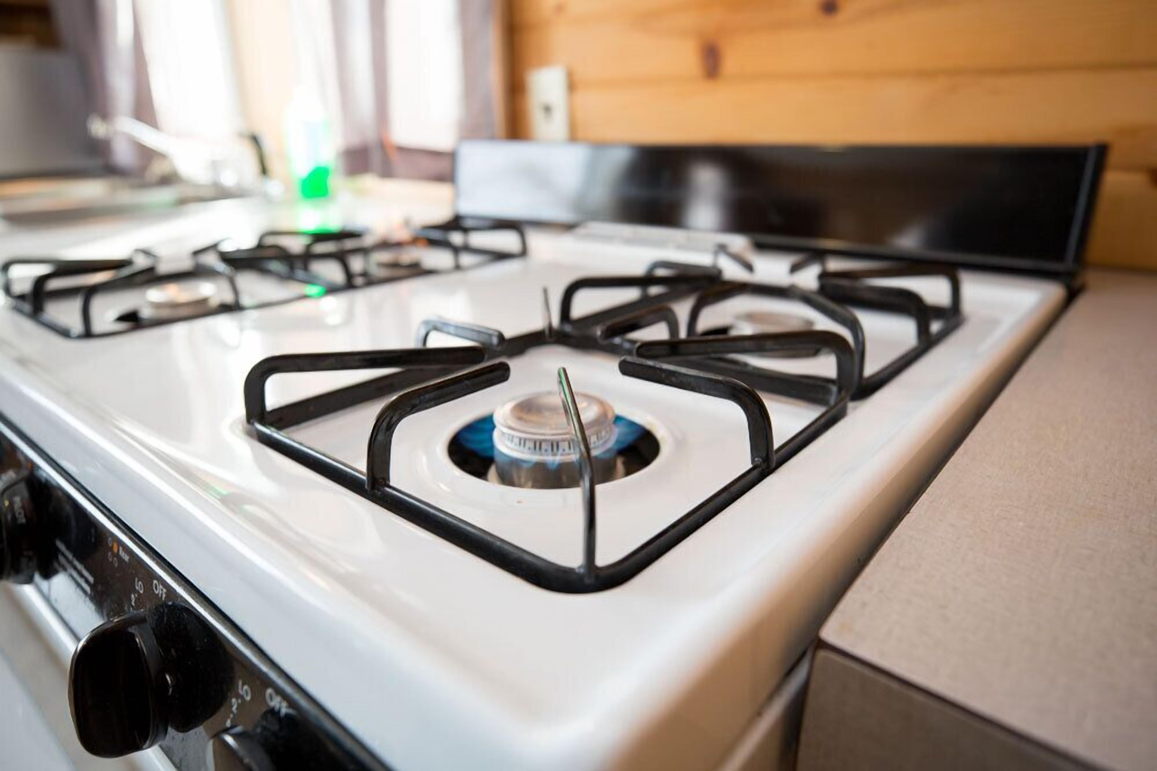 A kitchen with a white stove, black burners, and a gas knob.