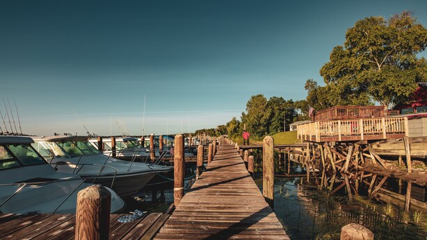 A wooden dock leading to a marina with boats docked on either side. - River Bend's Resort (Baudette)