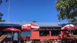 A River Bend Resort with outdoor seating and red umbrellas. - River Bend's Resort (Baudette)