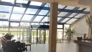 A spacious lobby with a high ceiling, large windows, and a view of the outdoors. - Hotel Bielany (Kobierzyce)