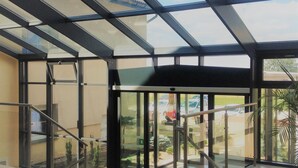 A spacious indoor area with a glass ceiling, a staircase, and a view of the outdoors. - Hotel Bielany (Kobierzyce)