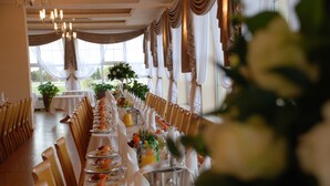 A long dining table with chairs, a chandelier, and draped curtains. - Hotel Bielany (Kobierzyce)