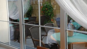 A glass-enclosed patio with wicker furniture and a table set for dining. - Hotel Bielany (Kobierzyce)