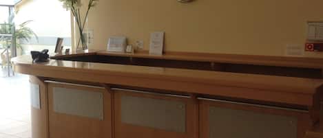 Un mostrador de recepción con un reloj, un calendario y un cartel que dice 'RECEPCJA'.