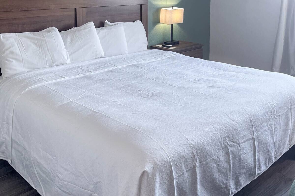 A neatly made bed with white linens in a hotel room.