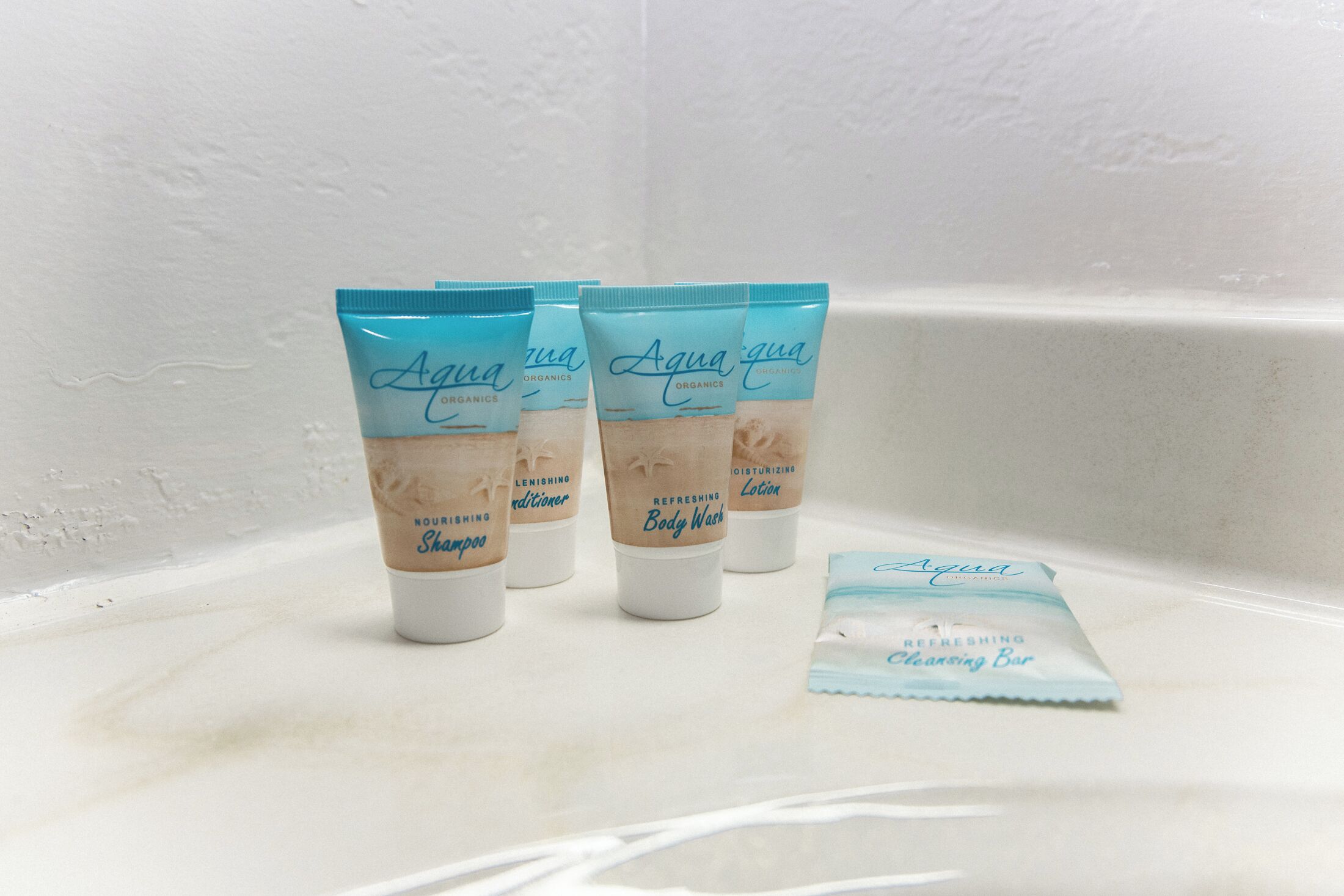 Four Aqua Organics body wash tubes and a cleansing bar on a white surface.