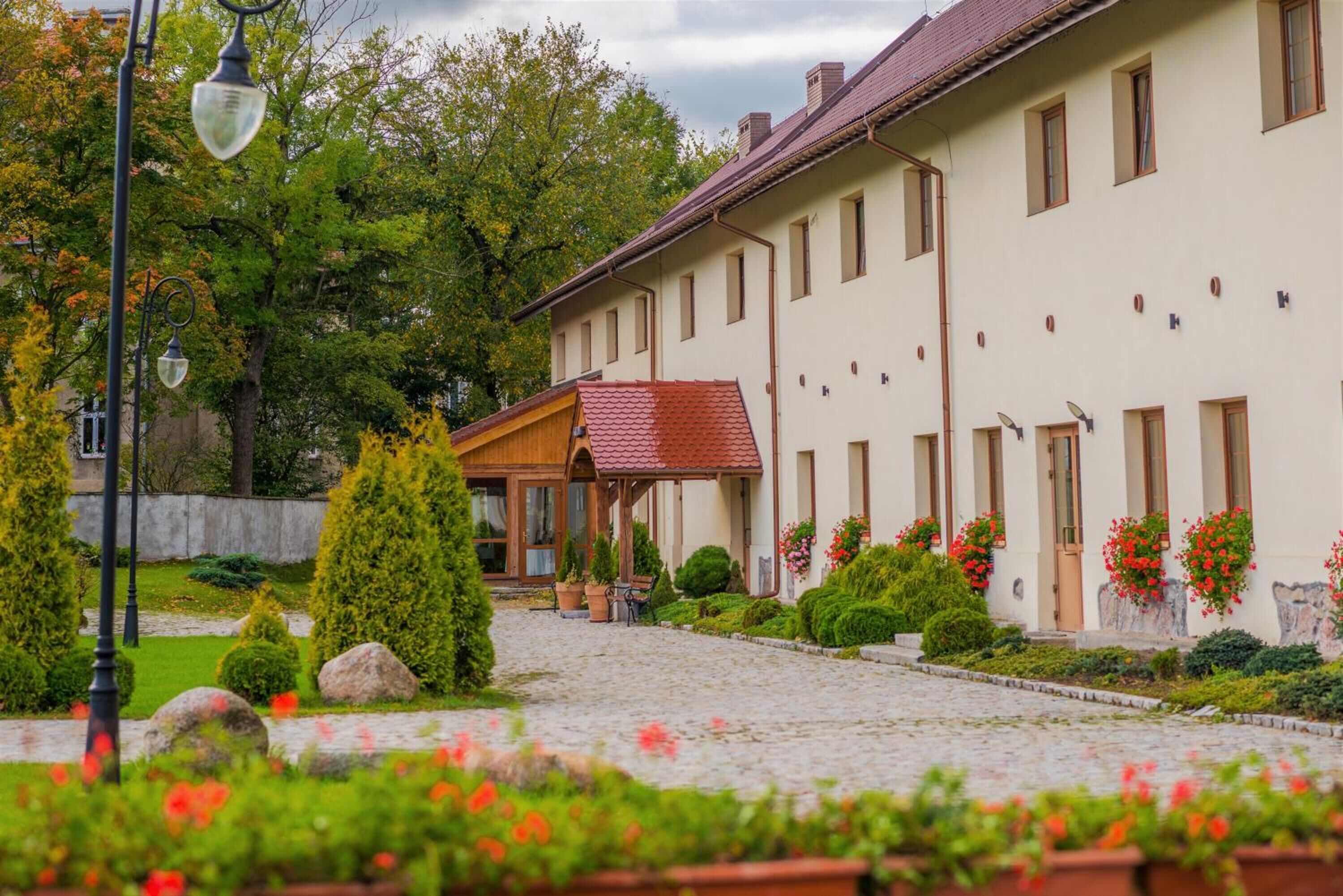 A traditional building with a cobblestone courtyard, potted plants, and a wooden structure with a red roof.