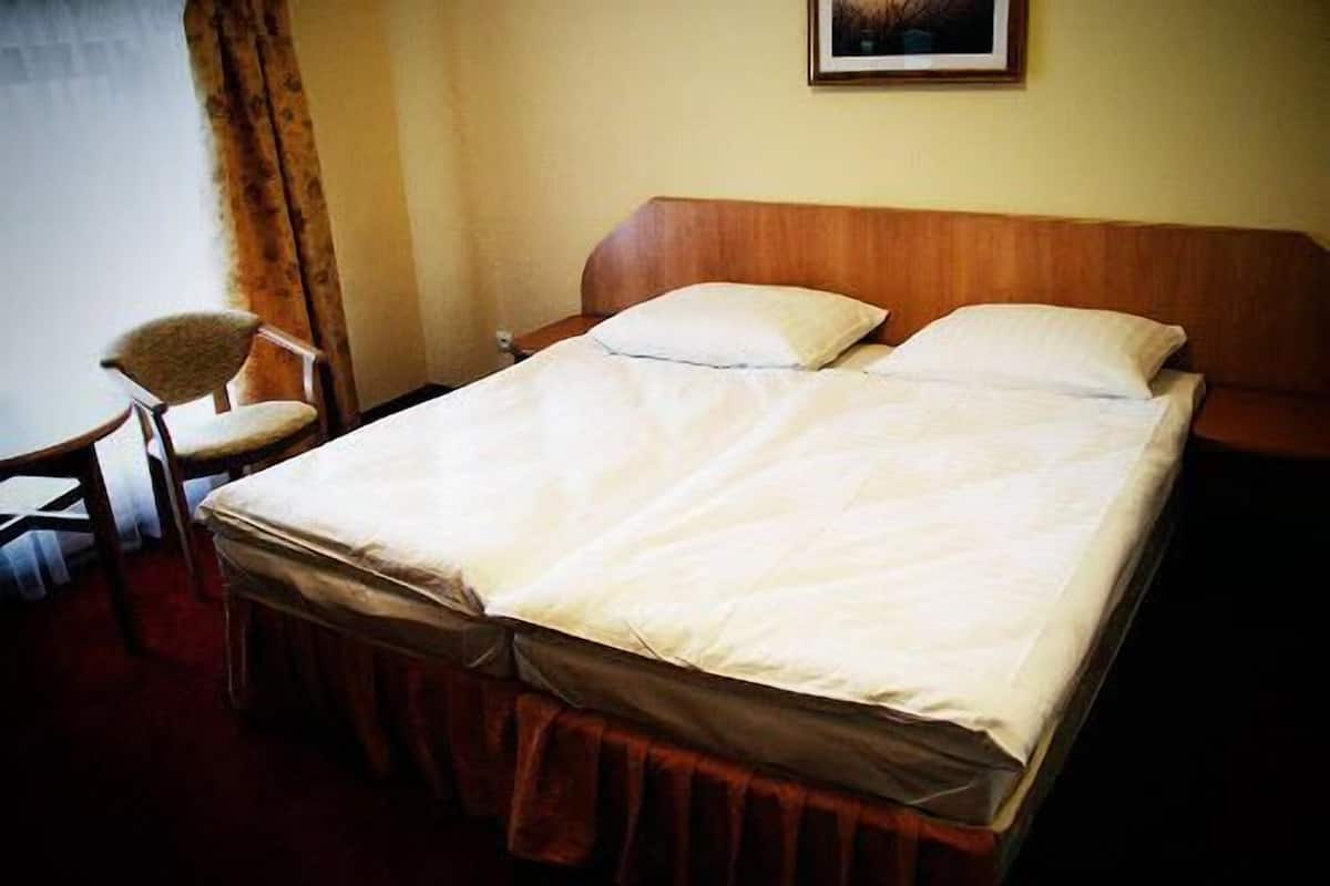 Una habitación de hotel con una cama, una silla y un cuadro en la pared.