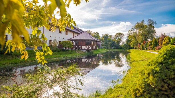 A riverside building with a wooden deck and a small pavilion. - Hotel Karczyce (gmina Kostomloty)
