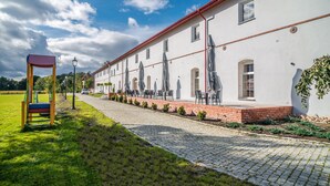 A building with a paved walkway, outdoor seating, and a swing set. - Hotel Karczyce (gmina Kostomloty)