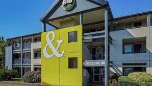 A B&B building with a prominent yellow and white sign, a balcony, and a clear sky.