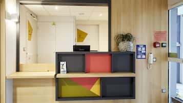 A reception area with a wooden desk, a phone, and a plant.