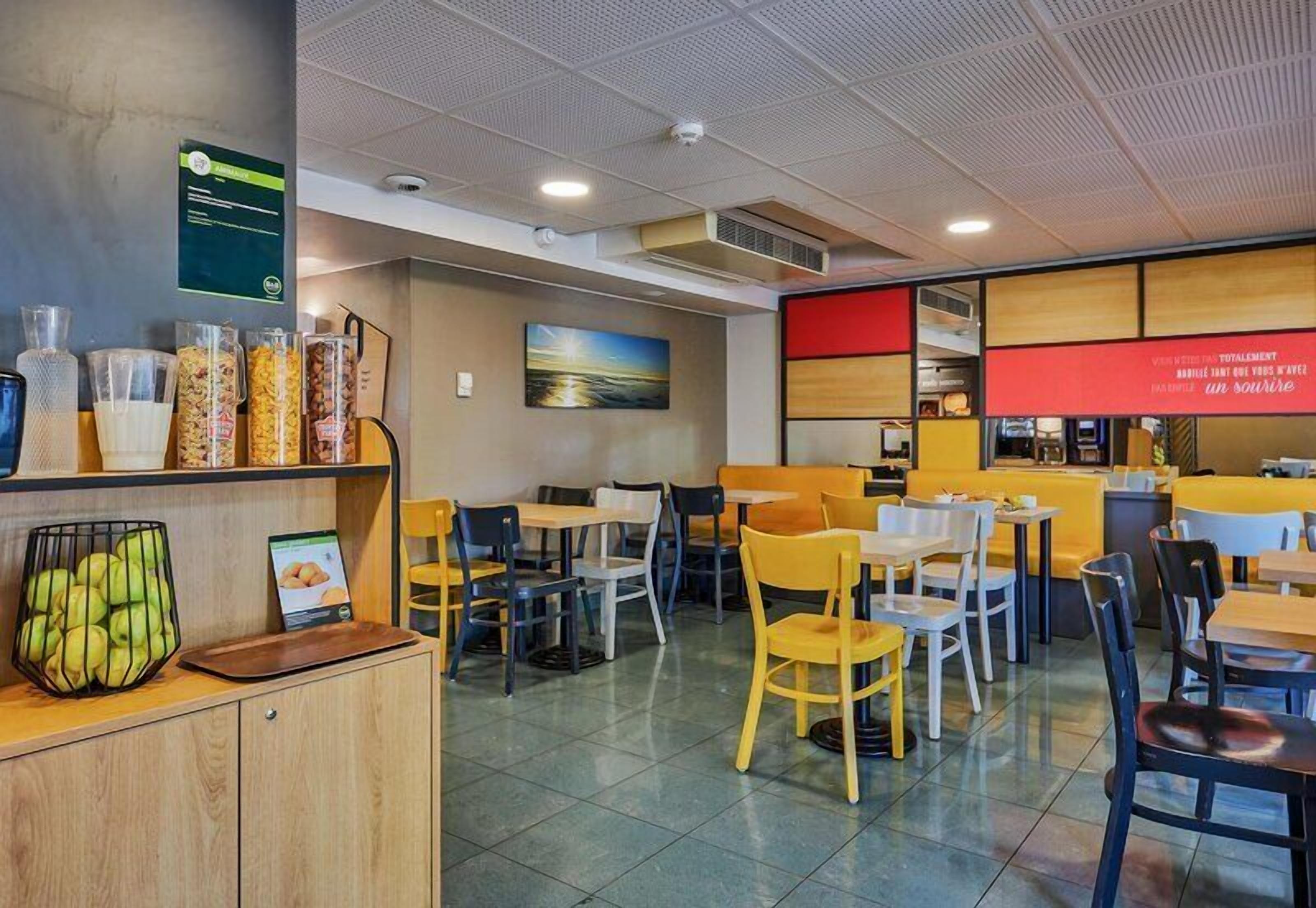 A restaurant with a counter, seating area, and a menu board.