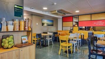 A restaurant with a counter, seating area, and a menu board.