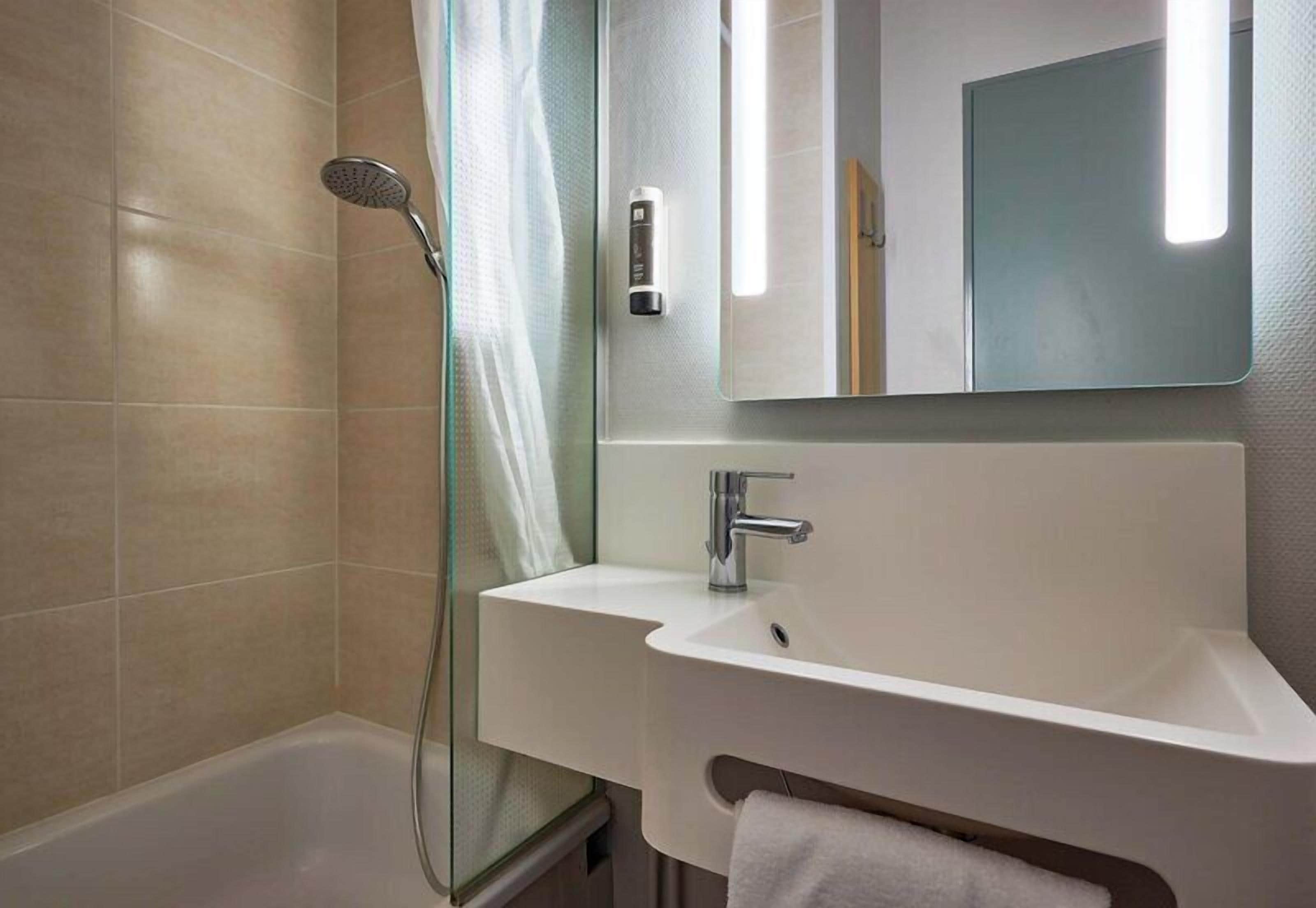 Une salle de bain moderne équipée d’une douche, d’un lavabo et d’un miroir.