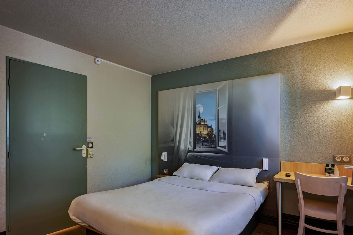 Una habitación de hotel con cama, escritorio y silla.