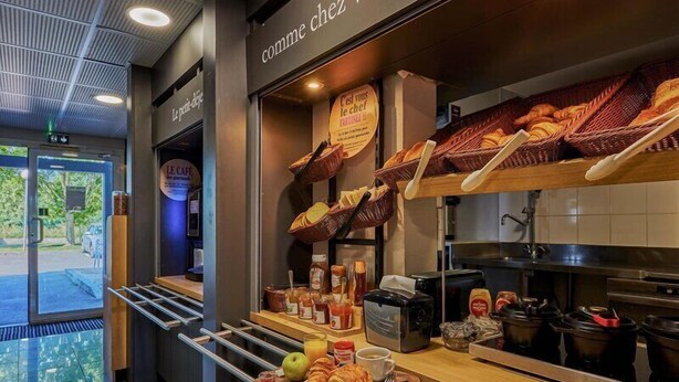 A breakfast buffet area with baskets of bread, pastries, and fruits.