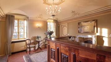 Un'ampia stanza con un'elegante vetrina in legno, un lampadario, un camino e un grande specchio.