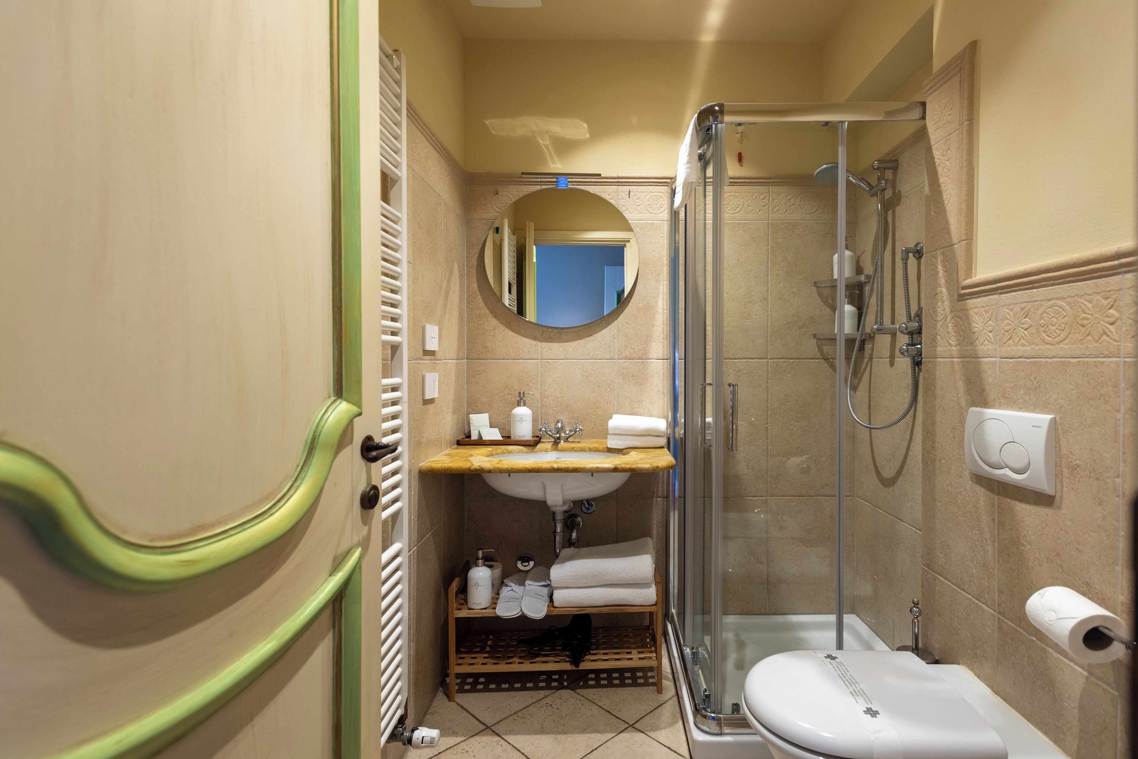A compact bathroom with a sink, mirror, toilet, and shower.