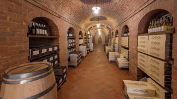 Una cantina vinicola con pareti in mattoni, botti di legno e scaffali pieni di bottiglie e casse di vino.