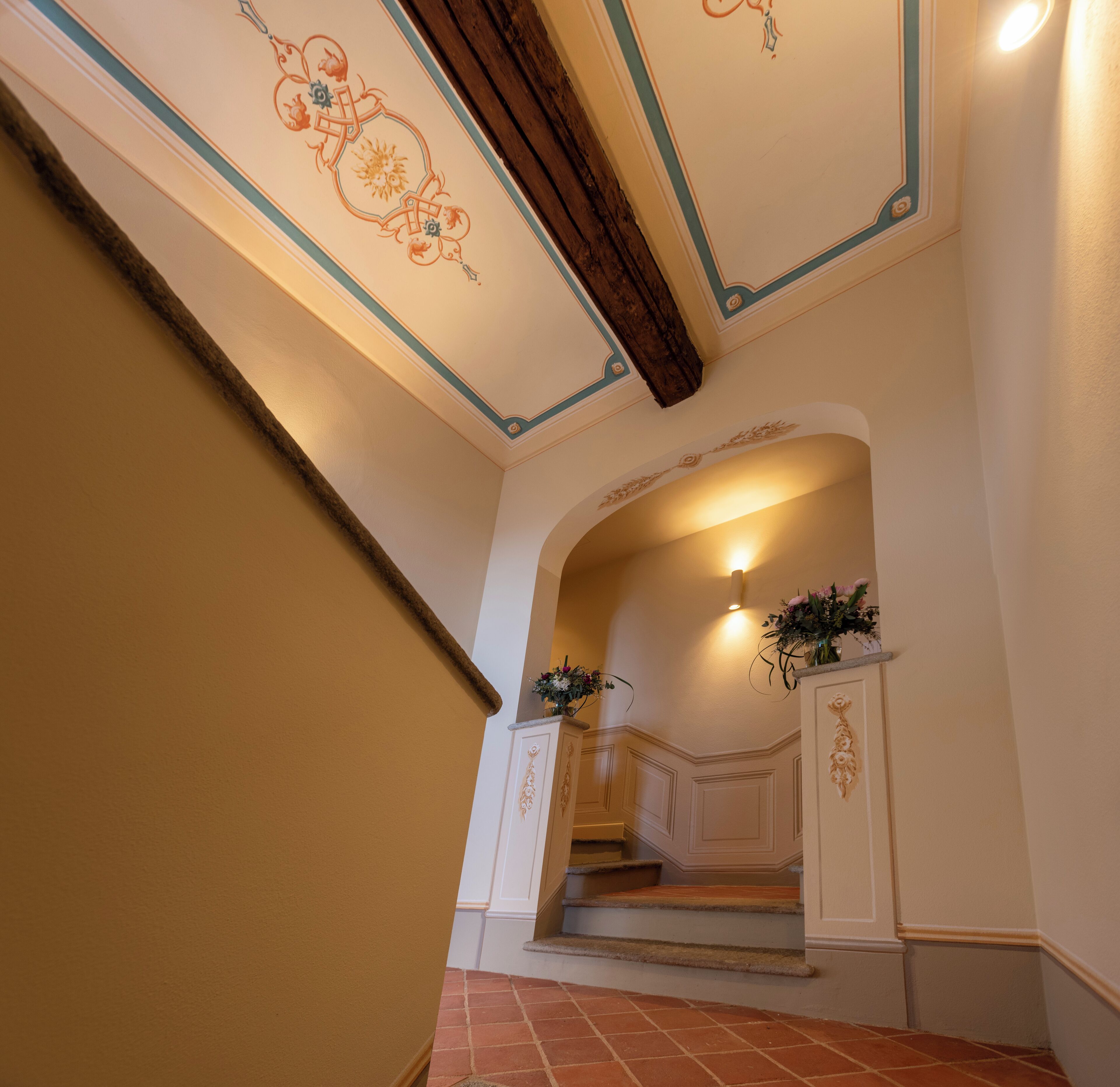 A grand staircase with ornate ceiling decorations and a warm, inviting atmosphere.