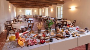 Un espace repas avec plusieurs tables préparées pour le petit-déjeuner, proposant une variété de plats et de boissons.